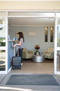 Hunter Gateway Motel في ميتلاند: امرأة مع حقيبة سفر أمام متجر