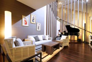 a living room with a white couch and a piano at Classic Kameo Hotel & Serviced Apartment, Rayong in Rayong