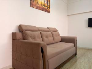 a brown couch against a white wall with a painting at My second home at Nashik in Nashik