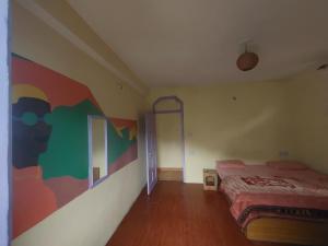 a bedroom with a bed and a painting on the wall at Nirvana Stays and Cafe in Manāli