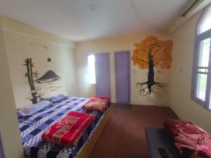 a bedroom with a bed and a tree mural on the wall at Nirvana Stays and Cafe in Manāli