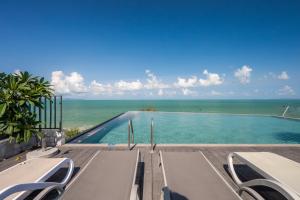 a swimming pool with the ocean in the background at Bayphere Residence Private Beach With Fitness and Pool in Na Jomtien
