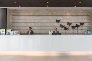 two men sitting at a counter in a lobby at Classic Kameo Hotel & Serviced Apartment, Rayong in Rayong
