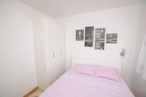 a white room with a bed with a pink pillow at Apartman Sinisa in Zlatibor