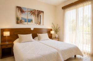 a bedroom with a white bed and a large window at Makis Inn Resort in Thermisía