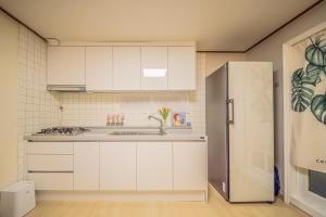 a kitchen with white cabinets and a stainless steel refrigerator at 선스테이 in Ilsan-ni +17 photos