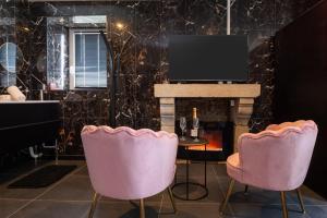 a living room with two pink chairs and a fireplace at Le Cocon secret - Sauna - Jacuzzi in Quimperlé
