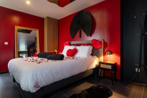 a bedroom with red walls and a bed with red pillows at Le Cocon secret - Sauna - Jacuzzi in Quimperlé