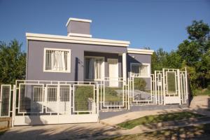 una casa con una valla blanca delante en Casa en Balneario Sol y Rio, en Villa Carlos Paz