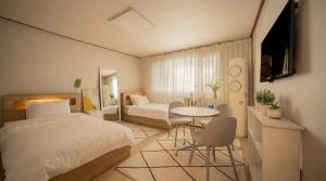 a bedroom with a bed and a table and a chair at 선스테이 in Ilsan-ni