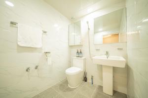 a white bathroom with a toilet and a sink at 선스테이 in Ilsan-ni