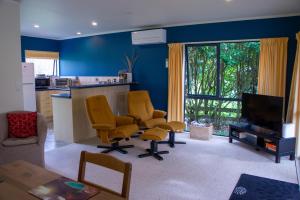 a living room with two yellow chairs and a kitchen at Minffordd Cottage in Feilding