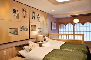 a bedroom with two beds and pictures on the wall at Seikoro Ryokan - Established in 1831 in Kyoto