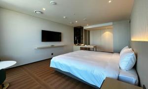 a bedroom with a white bed and a flat screen tv at Ulsan Tanibay Hotel & Wedding in Ulsan +40 photos