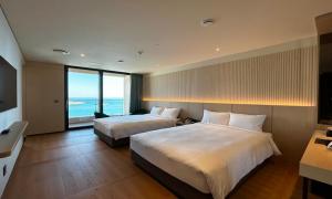 two beds in a hotel room with a view of the ocean at Ulsan Tanibay Hotel & Wedding in Ulsan