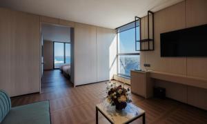 a living room with a television and a table with flowers on it at Ulsan Tanibay Hotel & Wedding in Ulsan