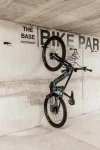 ein Fahrrad, das in einer Parkgarage an einer Wand hängt in der Unterkunft The Base Andermatt in Andermatt + 27 Fotos