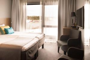 a hotel room with a bed and a chair and a window at Scandic Laholmen in Strömstad