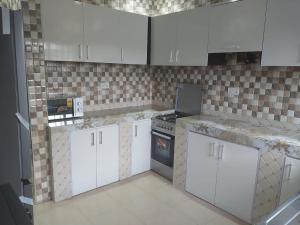 a kitchen with white cabinets and a stove at Eldu Villa in Kokrobite