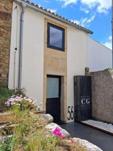 a white building with a black door and some flowers at Casa Gafura in Noya