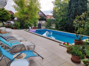 a pool with chaise lounge chairs and a swimming pool at Aquasol Apartman in Siófok
