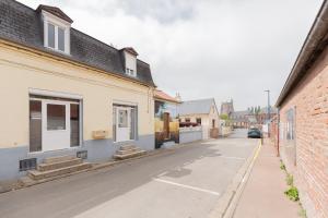an empty street with buildings and a car on the road at Gîte Escale En Baie De Somme in Saint-Blimont