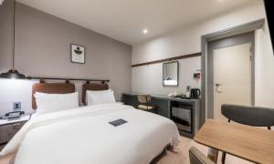 a bedroom with a large white bed and a desk at Pohang Mansion 6 Hotel in Pohang