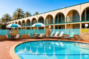 a pool in front of a hotel with chairs and umbrellas at Kings Inn Anaheim at The Park & Convention Center in Anaheim