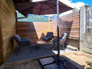 a patio with chairs and a table and an umbrella at Apartment type f1 to in Sainte-Hélène-sur-Isère