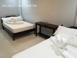 two beds in a room with a table and towels at La Famille in Baguio