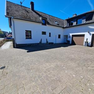 a white house with a garage and a driveway at Nest and Nature Strauch in Simmerath
