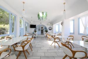 a restaurant with white tables and chairs and windows at Stratos Apartments & Studios in Parikia