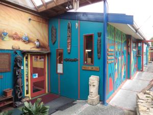 a blue building with a store with a statue in front at Global Village Travellers Lodge in Greymouth