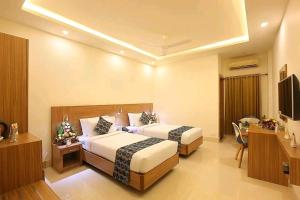 a hotel room with two beds and a desk at Heyday INN in Pathanāmthitta