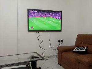 a television hanging on a wall in a living room at SKY BLUE guest house in Buea