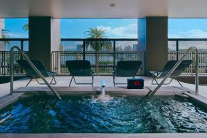 a hot tub in a hotel room with chairs and a clock at FAV LUX Miyazaki in Miyazaki