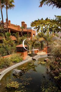 a pond in front of a building with palm trees at Casa Lucia in Palm-Mar