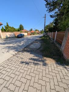 a brick road with a fence and a car parked on it at Dunakanyar Bed & Breakfast Panzio in Göd +4 photos