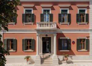 a pink building with green shuttered windows and a doorway at Bella Venezia in Corfu