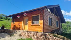 a small wooden house with a stone wall at Cabana Laura in Tîrnăveni