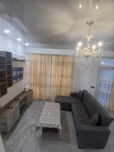 a living room with a couch and a chandelier at Квартира возле стадиона in Kobuleti
