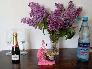 a table with two bottles of wine and a vase with purple flowers at Birken Loft am Meer in Neustadt am Rübenberge