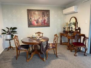 a dining room with a table and chairs and a painting at The Penguins Nest in Oamaru