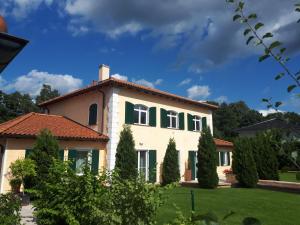 a large house with green shuttered windows and trees at "Zweisam" am Scharmützelsee - Ferienwohnung mit mediterranem Charme in Diensdorf-Radlow +6 photos