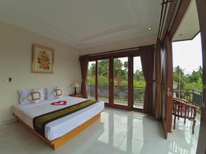 una camera con un grande letto e un balcone di Kubu Taman Home Stay ad Ubud