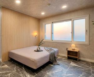 a bedroom with a bed and a window at Billy Hostel in Busan
