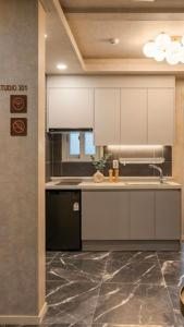 a kitchen with white cabinets and a black dishwasher at Billy Hostel in Busan