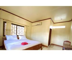 a bedroom with a bed with a red hat on it at Johnny Guesthoues and Restaurant in Ban Donsôm Tai