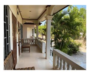 a porch of a house with a bench and palm trees at Johnny Guesthoues and Restaurant in Ban Donsôm Tai
