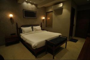 a bedroom with a large bed with white sheets and pillows at Hotel manju श्री in Pachmarhī